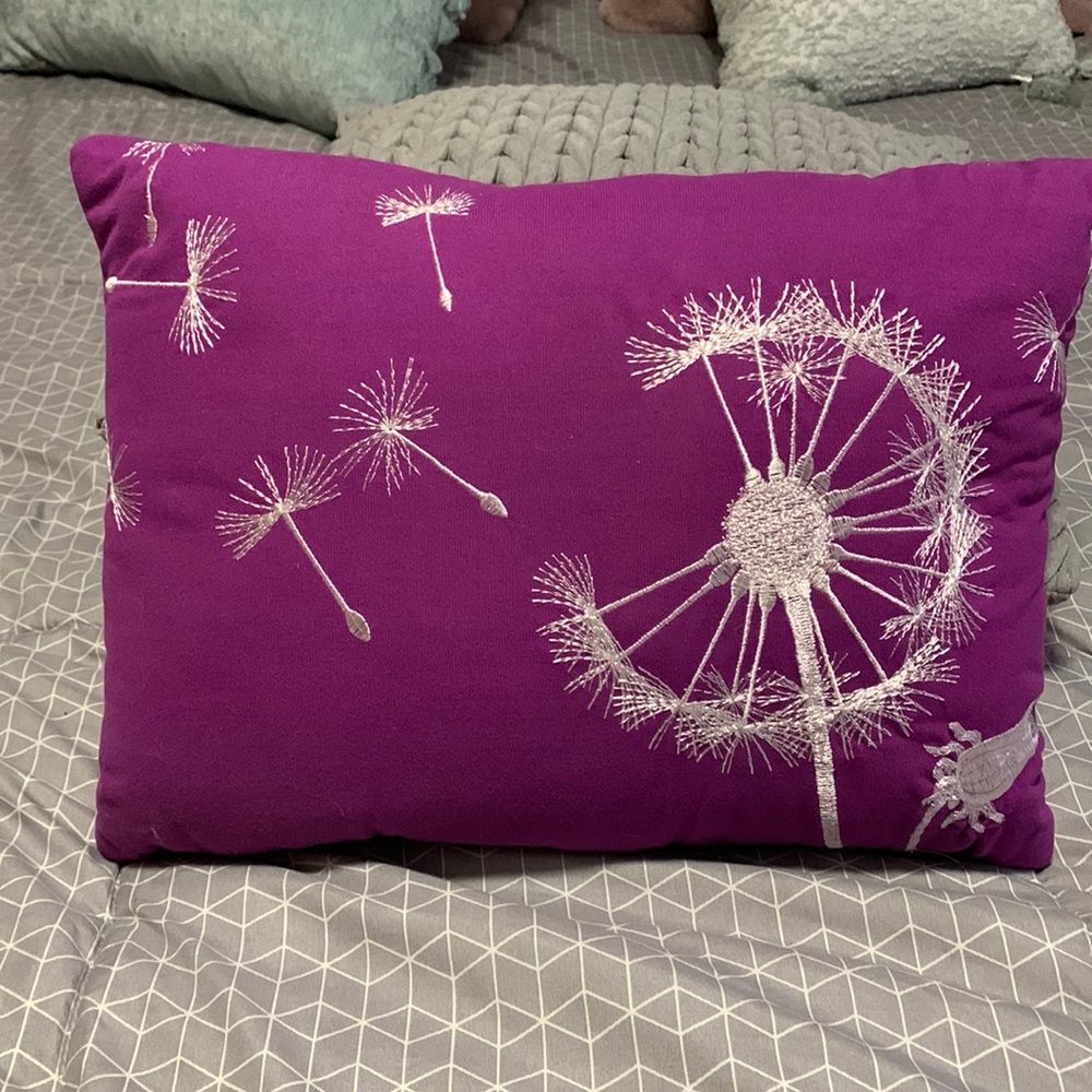 Decorative pillow in bright purple with white stitching.